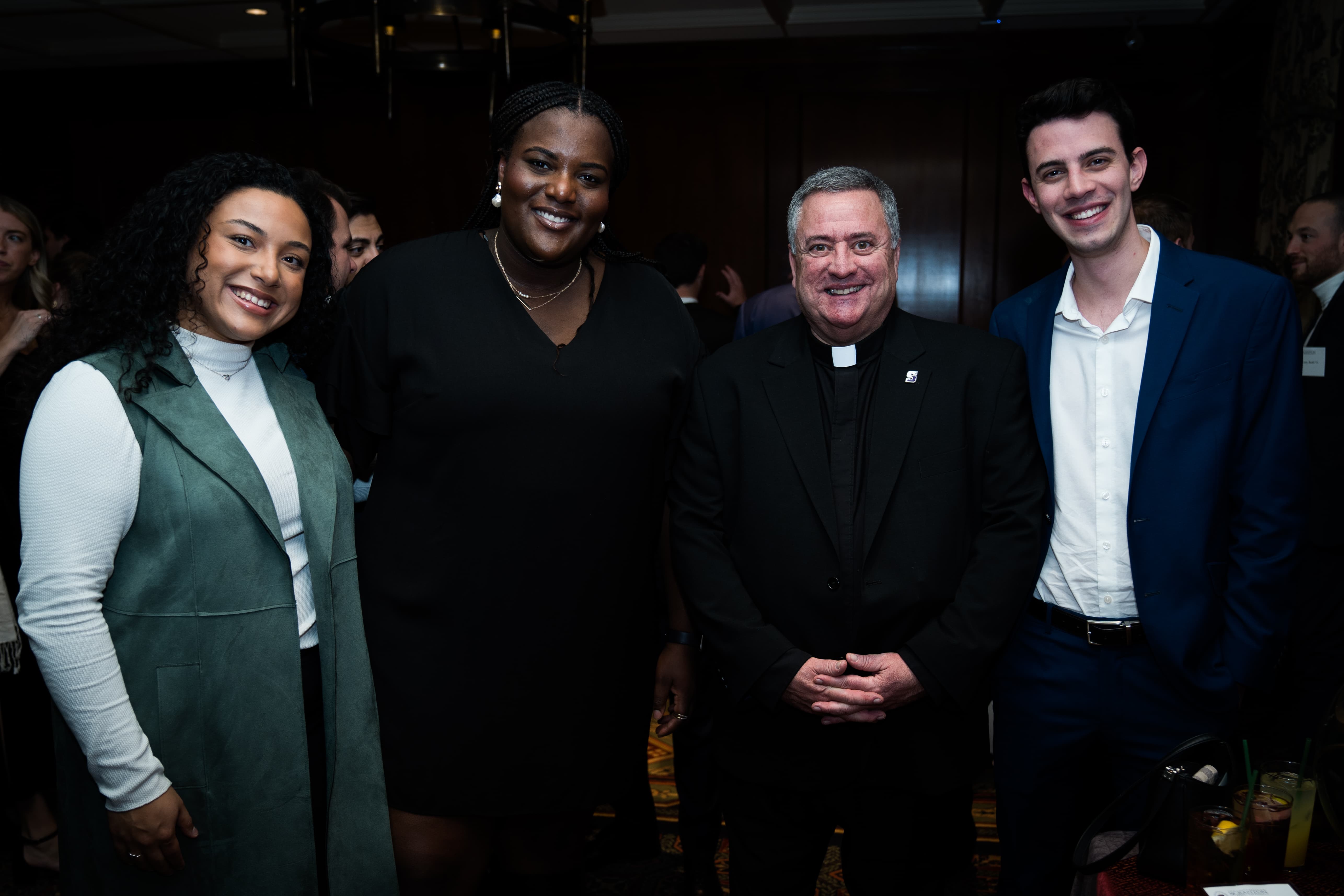 From left, Taylor Roman '21, Breanna Cole '21, Rev. Joseph G. Marina, S.J., University president, and Jeffrey Colucci '21 celebrate the Christmas season together at the New York Athletic Club on Dec. 2, 2022.
